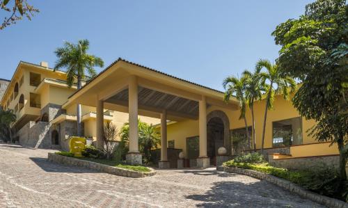 un edificio giallo con palme di fronte di Camino Real Acapulco Diamante ad Acapulco