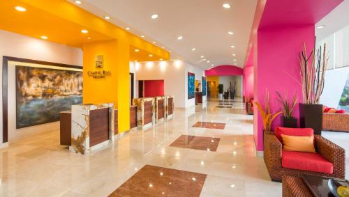 un hall avec des murs et des chaises roses et jaunes dans l'établissement Camino Real Veracruz, à Veracruz