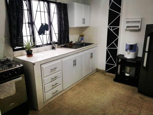 a kitchen with white cabinets and a sink and a window at Hermoso apartamento en el centro histórico de San Gil I 2 in San Gil