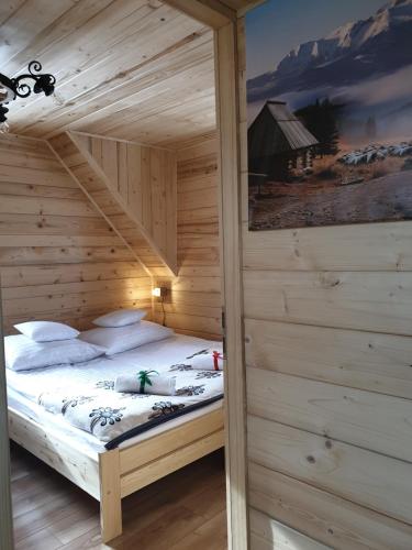 a bedroom with a bed in a wooden cabin at Domek Przekolec in Szaflary