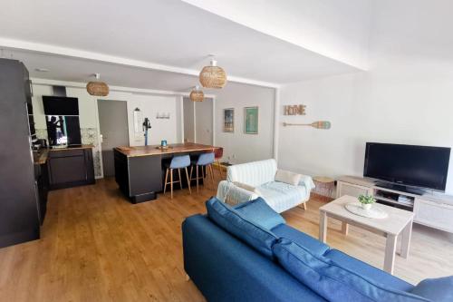 sala de estar con sofá azul y cocina en Duplex House With Large Terrace And Garden, en Moliets-et-Maa