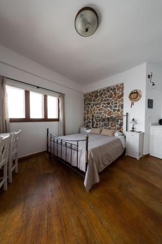 a bedroom with a bed and a stone wall at Smaro Studios in Firostefani