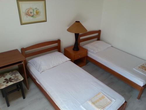 two beds in a room with a table and a lamp at Hostel Saint Ursula Rooms in Dubrovnik
