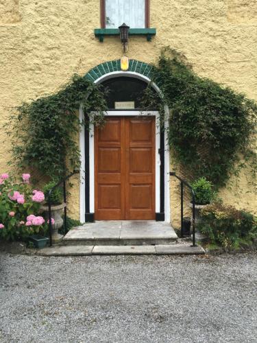 a wooden door on a building with flowers at Ballyglass Country House in Tipperary
