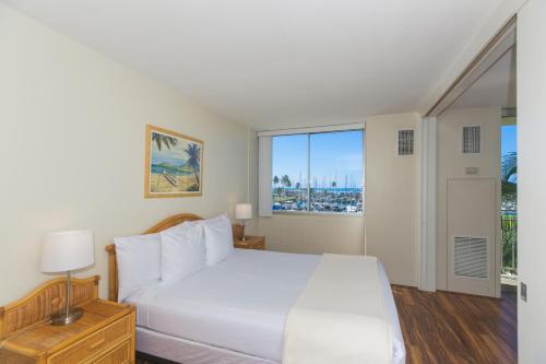 a bedroom with a white bed and a large window at Ilikai Marina 382 Yacht Harbor View 1BR in Honolulu