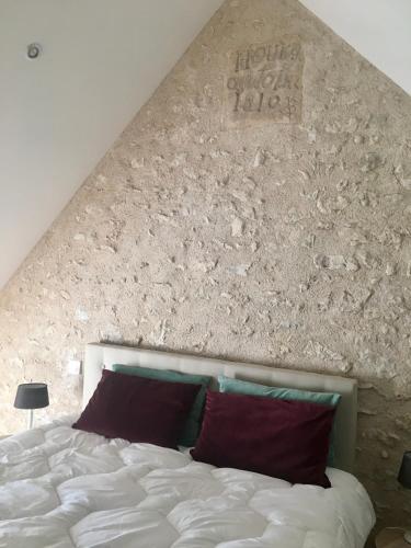 - une chambre avec un lit blanc et un mur en pierre dans l'établissement Les gîtes du Val de Chambord, à Huisseau-sur-Cosson