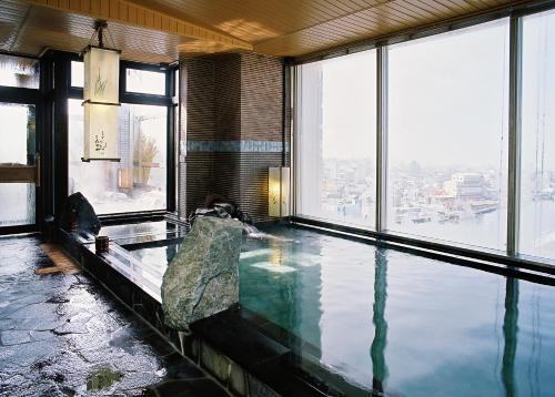a swimming pool in a building with a large window at Dormy Inn PREMIUM Kushiro in Kushiro