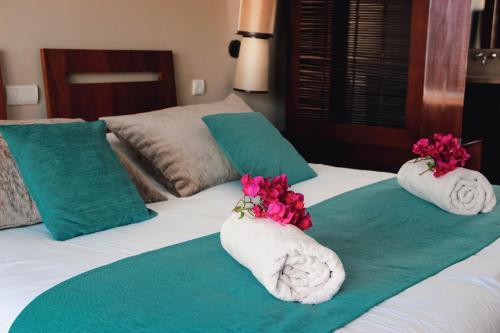 two towels with flowers on top of a bed at La Perle du Lagon in Le François