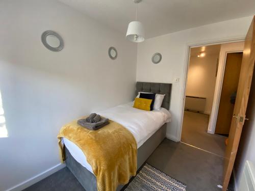 a bedroom with a bed with a yellow blanket on it at Marie’s Serviced Apartment 2 bed Olivier Court in Bedford