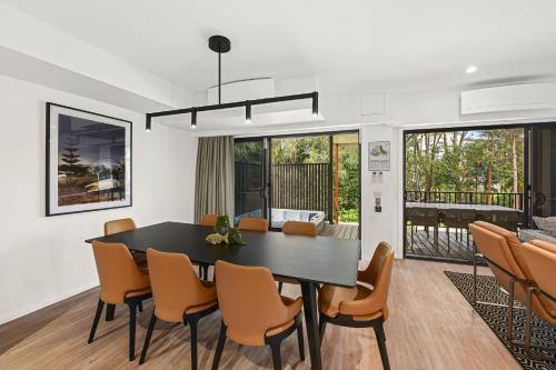 a dining room and living room with a black table and chairs at Club Wyndham Flynns Beach, Trademark Collection by Wyndham in Port Macquarie