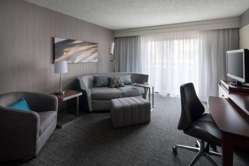 a hotel room with a couch chair and a television at Sonesta Select Los Angeles LAX El Segundo in El Segundo