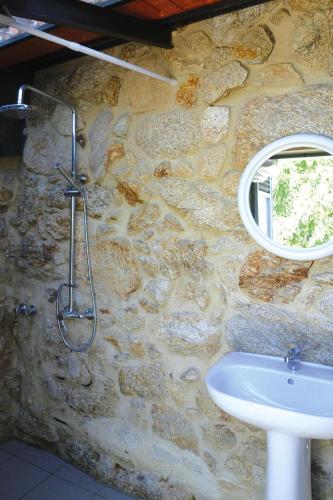 a stone bathroom with a sink and a mirror at Stone House by Caima River with Pool in Vale de Cambra