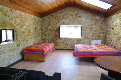 a room with two beds and a table and a window at Stone House by Caima River with Pool in Vale de Cambra