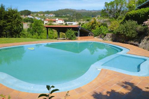 a large blue swimming pool in a yard at Stone House by Caima River with Pool in Vale de Cambra