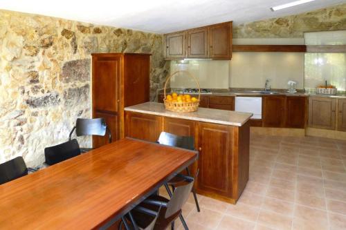 a kitchen with wooden cabinets and a table and a counter at Stone House by Caima River with Pool in Vale de Cambra