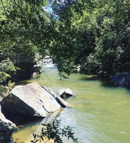 a river with some rocks and trees and water at Chalé na Chapada, com acesso ao Rio São Miguel in Sao Jorge