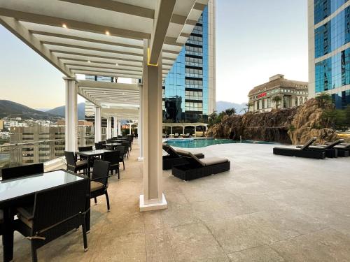 een patio met tafels en stoelen en een zwembad in een gebouw bij Safi Royal Luxury Metropolitan in Monterrey