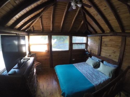 1 dormitorio en una cabaña de madera con 1 cama en La Cabaña de la casona en Don Torcuato