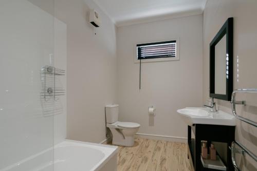 a white bathroom with a toilet and a sink at Cardrona Valley Escape - Cardrona Holiday Home in Cardrona