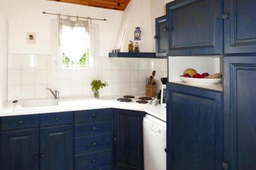 - une cuisine avec des placards bleus, un évier et un bol de fruits dans l'établissement Chalet near Mont St Michel & Nature Trails, à Céaux