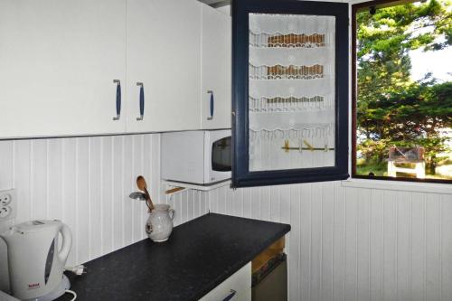 une cuisine avec des placards blancs et un comptoir noir dans l'établissement Holiday Home, Portbail, à Portbail