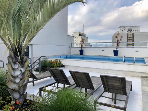 un balcon avec des chaises et une piscine dans un immeuble dans l'établissement SeuLar o conforto de um Lar em Qualquer Lugar, à São Paulo