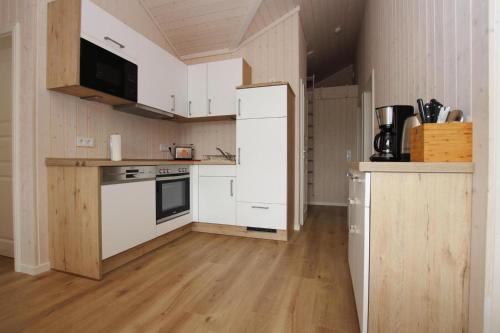 a small kitchen with white appliances and wooden floors at Ferienhaus Larsson mit Sauna am Dümmer See, Dümmer in Dümmer