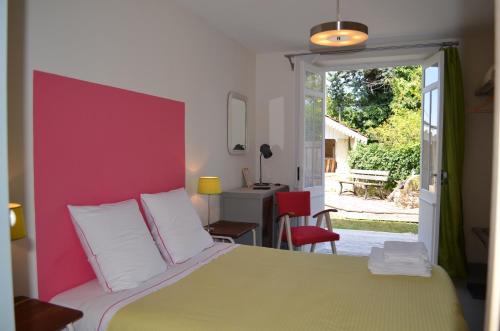 a bedroom with a large bed with a pink wall at Le Jardin Secret in Gauriac
