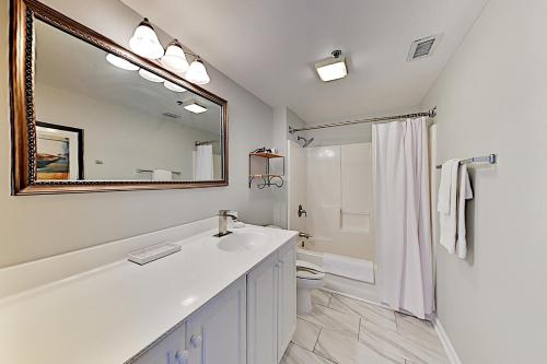 Baño blanco con lavabo y espejo en Water Street Condos III, en Wilmington