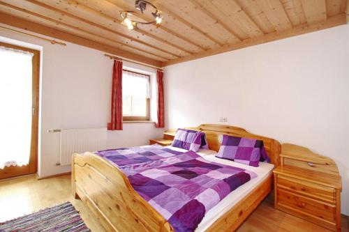 1 dormitorio con cama de madera y almohadas moradas en Holiday flat Bachmaier, Krimml en Krimml
