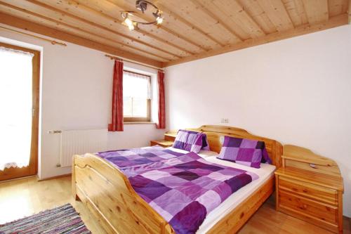 a bedroom with a wooden bed with purple pillows at House in Krimml near Waterfalls & Hiking Trails in Krimml