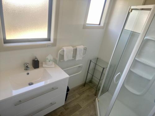 a white bathroom with a sink and a shower at Comfortable & Close to Town in Twizel