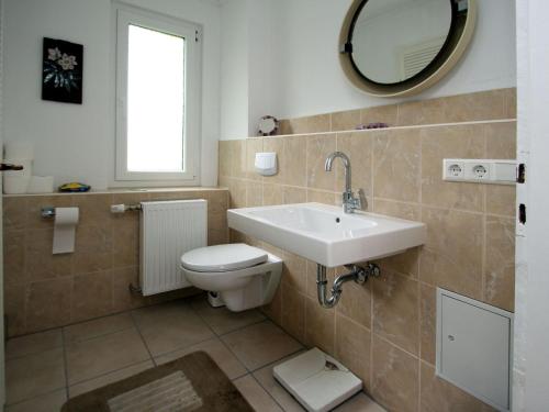 a bathroom with a toilet and a sink and a mirror at Holiday home Seeidyll, Teupitz in Teupitz