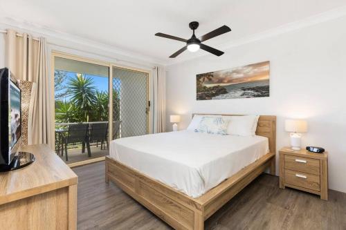 a bedroom with a bed and a tv and a balcony at 2Bed Beachfront Apartment - Holiday Management in Kingscliff