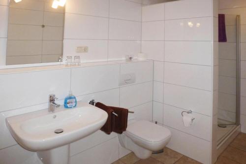 La salle de bains blanche est pourvue d'un lavabo et de toilettes. dans l'établissement Apartment Landhaus Markus, Süderschwei, à Süderschwei