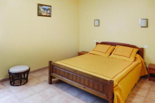 Cette chambre comprend un lit avec des draps jaunes et un tabouret. dans l'établissement Semi-detached house, Beaucaire, à Beaucaire