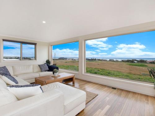 a living room with two white couches and large windows at Ocean Mist in Port Fairy