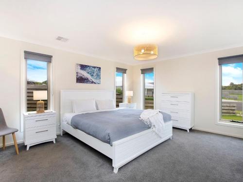 a white bedroom with a white bed and windows at Ocean Mist in Port Fairy