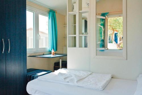 1 dormitorio con cama, mesa y ventana en Caravan Park Kovacine, Cres, en Cres