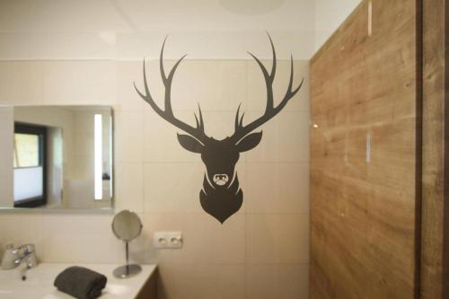 a bathroom with a deer head on the wall at Chalet Charivari Inzell, Inzell in Inzell