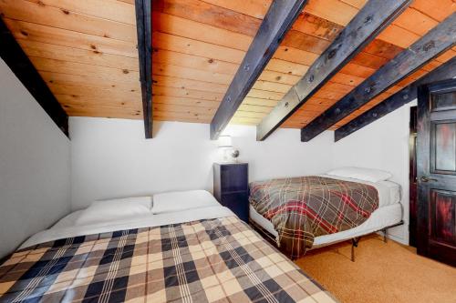 two beds in a room with wooden ceilings at Back Country Basecamp in Stateline