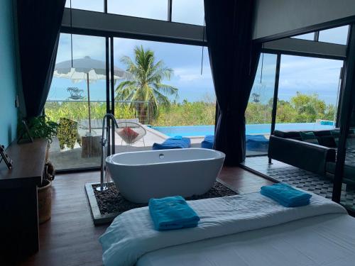 a bathroom with a tub and a view of a pool at Sky Villas Philippa with Free Car in Laem Set Beach
