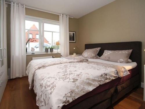 um quarto com uma cama grande e uma janela em Apartment Alte Liebe, Dornumersiel em Dornumersiel