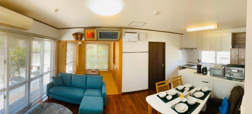 a living room with a blue chair and a kitchen at ゆくい家 in Ginowan