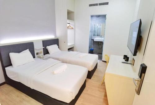 a hotel room with two beds and a flat screen tv at BOOKME HOTEL in Johor Bahru