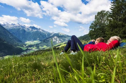 two women laying in the grass on top of a mountain at Apartment in Hohe Tauern with Mountain Views in Neukirchen am Großvenediger
