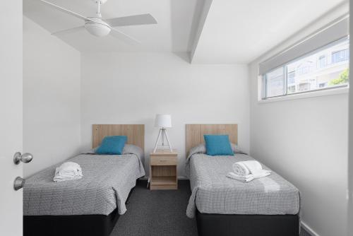 two twin beds in a room with a window at Seaside Holiday Resort in Fingal Bay