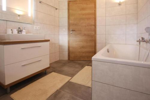 a bathroom with a white tub and a sink at Chalet Gamsknogel mit privatem Pool und Whirlpool in Inzell