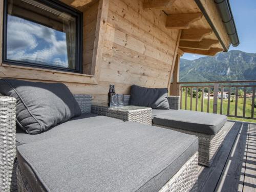 a porch with a couch and chairs on a deck at Chalet Gamsknogel mit privatem Pool und Whirlpool in Inzell