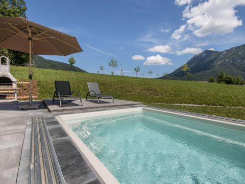 a swimming pool with two chairs and an umbrella at Chalet Gamsknogel mit privatem Pool und Whirlpool in Inzell